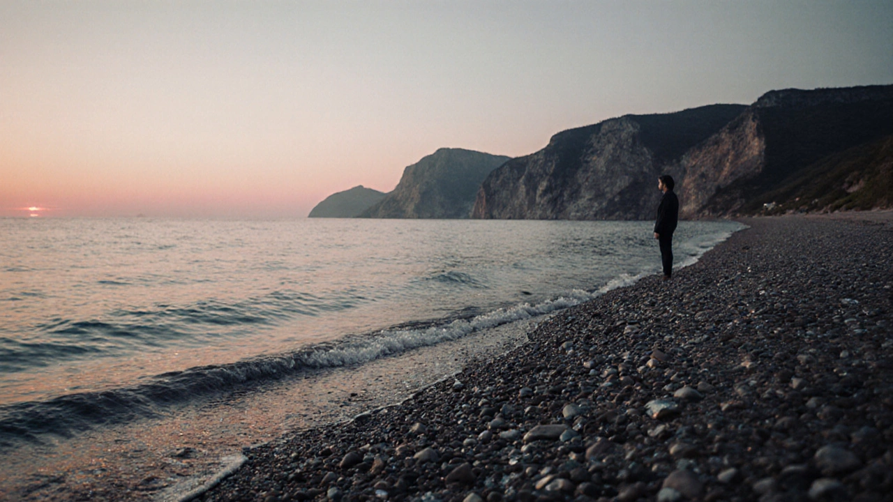 Тихий берег Чёрного моря в Крыму с блестящей галькой и закатом на фоне скал.